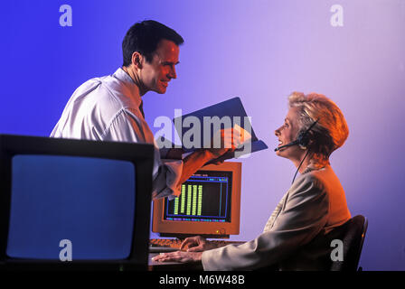 1996 historische zwei KAUKASISCHEN TELEFON VERKÄUFE LEUTE SITZEN AM COMPUTER SCHREIBTISCH IM BÜRO TRAGEN schnurgebundenes Telefon HEADSET Stockfoto