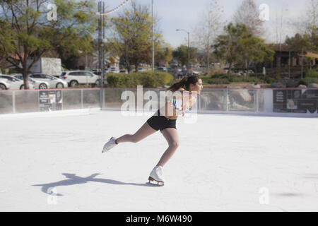 Jugendmädchen Eislaufen im Freien in Shorts und Bikini Oberteil im Südlichen Califiornia in 85 Grad im Winter Wetter Stockfoto