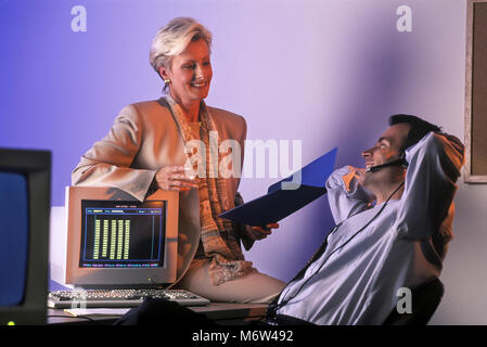 1996 historische zwei KAUKASISCHEN TELEFON VERKÄUFE LEUTE SITZEN AM COMPUTER SCHREIBTISCH IM BÜRO TRAGEN schnurgebundenes Telefon HEADSET Stockfoto