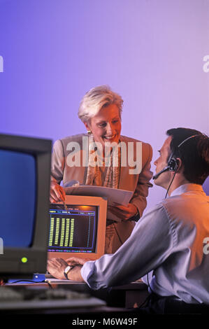 1996 historische zwei KAUKASISCHEN TELEFON VERKÄUFE LEUTE SITZEN AM COMPUTER SCHREIBTISCH IM BÜRO TRAGEN schnurgebundenes Telefon HEADSET Stockfoto