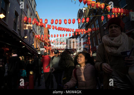 Leuchtend rote und gelbe Laternen sind aufgereiht über zwischen den Gebäuden erstellen einer Überdachung der Farbe für das chinesische Neujahr auf Gerrard Street, Soho, Chinatown in London, England, Vereinigtes Königreich bekannt. Lokale chinesische Gemeinschaft versammeln sich auf diese berühmte Straße in Central London, ist der Fokus von Feiern. Stockfoto