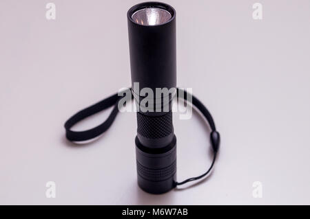 Taschenlampe mit handschlaufe auf weißem Hintergrund. LED Aluminium taschenlampe. Schwarze Taschenlampe. Stockfoto