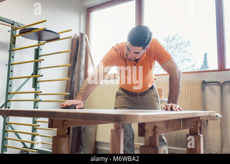 Tischler polieren und Lackieren einen Tisch in seiner Werkstatt Stockfoto