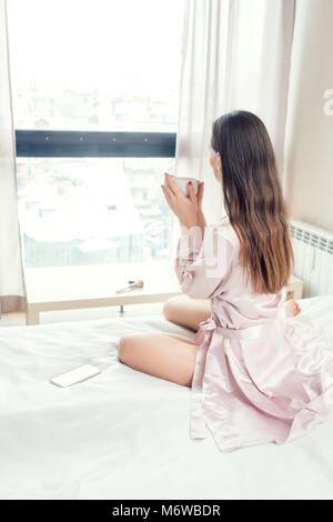 Frau, die Ihren ersten Kaffee am Morgen auf dem Bett Stockfoto