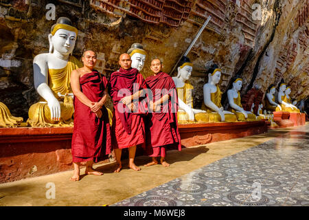 Buddhistische Mönche vor felszeichnungen an der Decke und Buddha Statuen an Kaw-goon Höhle, auch bekannt als Kawgun Cave Tempel oder Höhle des Stockfoto