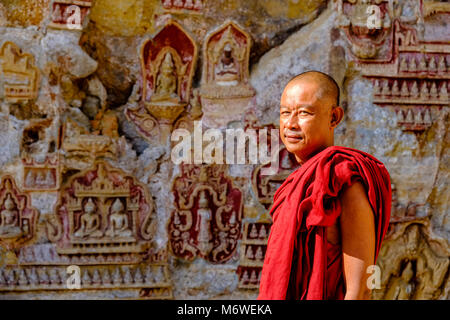 Ein buddhistischer Mönch steht vor felszeichnungen an der Decke bei Kaw-goon Höhle, auch als Kawgun Cave Tempel oder Grotte von Zehntausend Bu bekannt Stockfoto