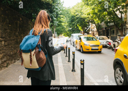 Ein junger Tourist girl mit einem Rucksack in einer grossen Stadt ist gerade eine Karte. Reise. Sightseeing. Stockfoto