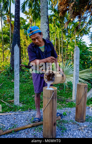 Ein lokaler Landwirt ist Gießen eine Kokospalme sap, Palm Saft, in einem Bambus Container Stockfoto