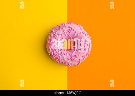 Ein rosa Donut auf farbigen Hintergrund. Stockfoto