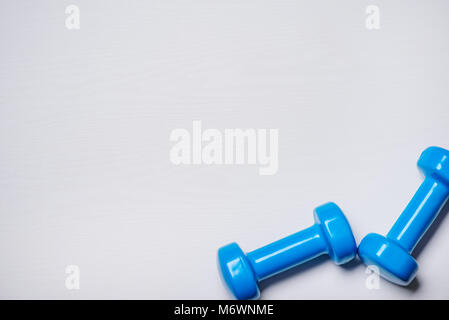 Zwei Kurzhanteln Blau liegen auf einem weißen Hintergrund mit einem Baum Textur. Stockfoto