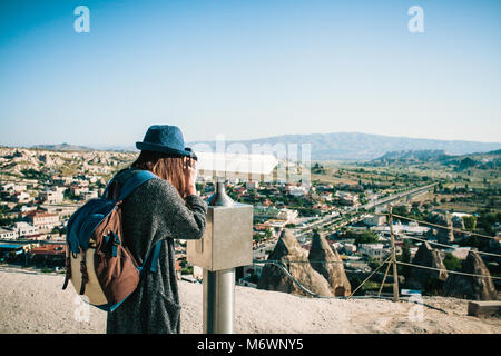 Ein Reisender mit einem Rucksack auf Sicht sieht durch ein Fernglas bei einem schönen Blick auf die Stadt von Göreme in Kappadokien in der Türkei. Reise. Wandern. Stockfoto