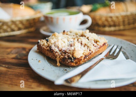 Close-up Stück süße Torte mit Dessert Gabel auf Untertasse gegen den Hintergrund von blurry Platten mit Essen auf hölzernen Tisch Stockfoto