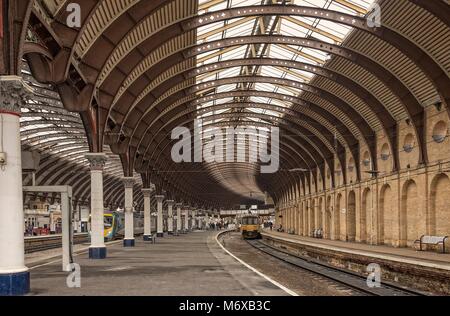 Der Bahnhof York Plattform betont die kunstvoll geschwungenen Dach und Architektur aus dem 19. Jahrhundert. Ein Zug wartet, abzuweichen. Stockfoto