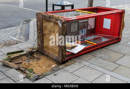 Eine zerstörte oder beschädigte Telefonzelle, die sich auf die Seite in London verliebt hat. Beschädigte call-Box über und auf dem Boden liegen Glasscherben gestürzt Stockfoto