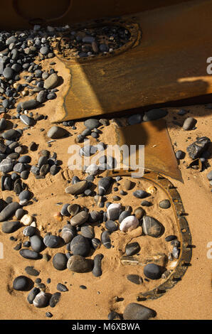 Alte havarierten Boot Luken und Rumpf Teile in der Strand Sand zwischen den Steinen, Peebles und Rumpf Teile begraben. Stockfoto