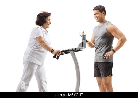 Ältere Frau Ausübung auf einem Laufband mit einem persönlichen Trainer auf weißem Hintergrund Stockfoto