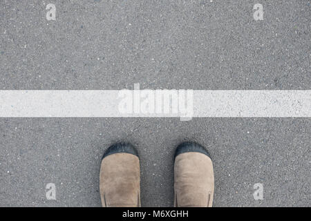 Braun Wildleder Schuhe stehen auf dem Asphalt Beton Boden vor der weißen Linie Stockfoto