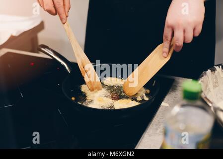 Frau braten Panierter Fisch in heißem Öl in der Pfanne Stockfoto