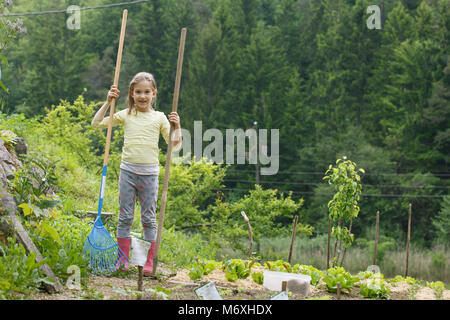 Kleines Mädchen, Gartengeräte, Spaß im Garten, Pflanzen, Gärtnerei, ihrer Mutter zu helfen. Glücklich, natürliche Kindheit Konzept. Stockfoto