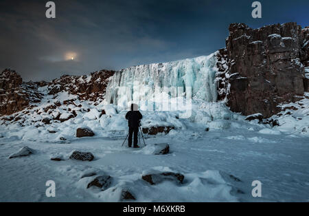 Fotograf Bilder aufnehmen, die von den gefrorenen Oxararfoss Wasserfall, den Nationalpark Thingvellir, Island. Unesco-Weltkulturerbe. Stockfoto