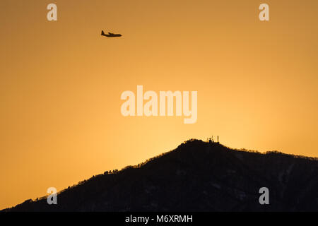 Eine japanische Marine Self Defence Force (JMSDF) Lockheed C-130R Herkules, die bei Sonnenuntergang über den Berg Tanzawa fliegen. Kanagawa, Japan. Stockfoto