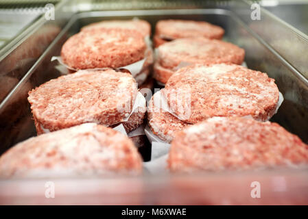 Metall Fach für gefrorenes Hackfleisch hamburger Pastetchen mit Ölpapier in einem Restaurant oder Metzgerei getrennt Stockfoto
