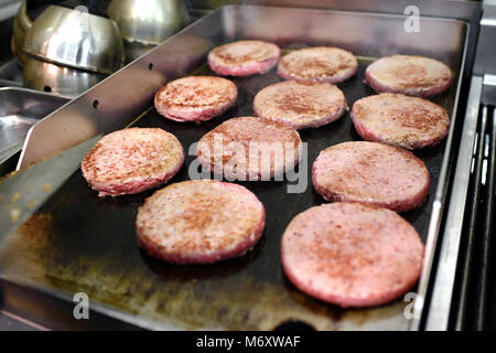 Reihen von ground Beef Burger Frikadellen kochen auf einem heißen Bratpfanne oder Kochplatte in einem Fast-Food-Restaurant in der Nähe zu sehen, der Fleisch- und Gerät Stockfoto