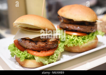 Bereit zum Hamburger auf ein Tablett mit frischem Salat Garnituren, Rindfleisch Patty, Speck gefüllt serviert Essen und geschnittenen Käse auf einem crusty Bun Stockfoto