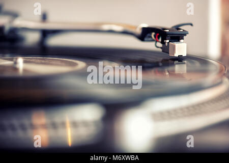 Low Angle Sicht auf eine Nadel auf die retro Vinyl Schallplatte Abspielen von Musik im Innenbereich zur persönlichen Unterhaltung Stockfoto