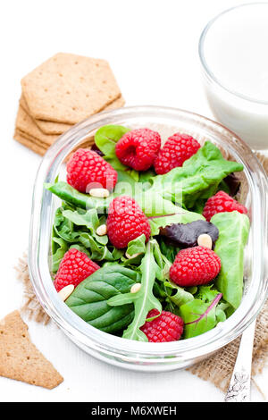 Grüner Salat mit Rucola und Beeren und Pinienkerne auf weißen Tisch mit Joghurt Stockfoto