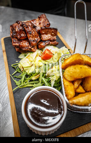 Gebratenes Fleisch mit Kartoffelecken und frische Rucola Stockfoto