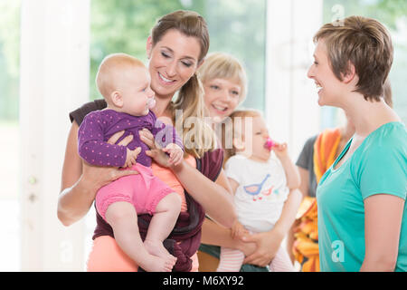 Gruppe von Frauen lernen, wie man Baby Tragetücher für Mutter-Kind Stockfoto