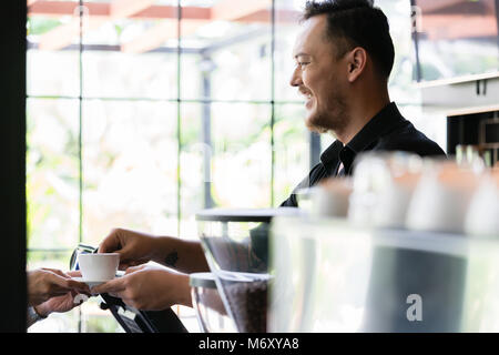 Barkeeper serviert einen kurzen Espresso zum Kunden Stockfoto