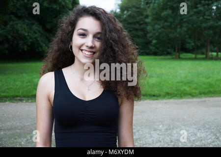 Schöne junge Frau mit brunette langes lockiges Haar in der Natur Stockfoto