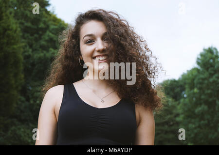 Happy brunette teenage Mädchen mit langen Locken in der Natur Stockfoto
