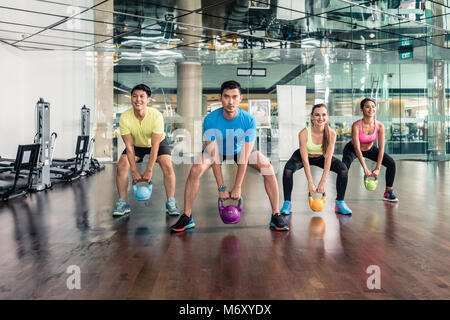 Volle Länge von vier fröhliche Menschen kettlebells Holding Stockfoto