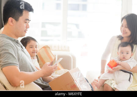 Chinesischer Mann scannen QR Code mit Smart Phone. Gerne asiatische Familie zu Hause, Natural Living Lifestyle im Innenbereich. Stockfoto