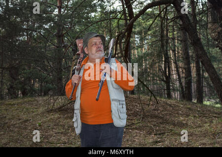 Portrait von schweren Junior Ranger mit zwei Gewehre stehen in dunklen Kiefernwald Stockfoto