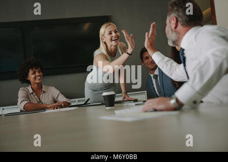 Geschäftsfrau, die eine hohe fünf zu den männlichen Kollegen während einer Konferenz. Geschäftsleute in Sitzung im Sitzungsraum. Stockfoto