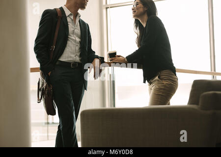 Zwei Kollegen gemeinsam im Büro und Sprechen während der Pause. Business Partner besprechen, während durch ein Geländer stehen. Stockfoto