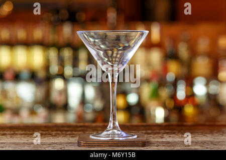 Eine saubere Martini Glas steht auf den unscharfen Hintergrund der Theke, eine traditionelle Bar Hintergrund Stockfoto