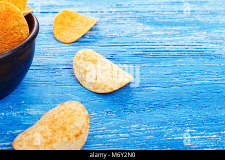 Kartoffelchips in einem Steingut Teller, Platte auf einem hölzernen Hintergrund steht. Bier Snack, ungesundes Essen Stockfoto