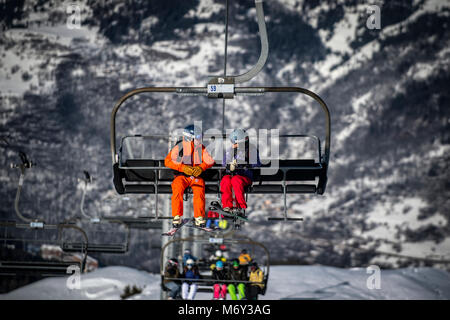 Ein männlicher Skilehrer spricht eine Frau auf einem Sessellift in den Französischen Alpen Courchevel. Stockfoto