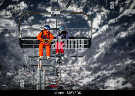 Ein männlicher Skilehrer spricht eine Frau auf einem Sessellift in den Französischen Alpen Courchevel. Stockfoto