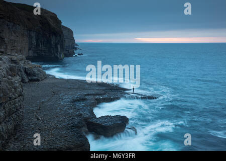 Einen einsamen Angler auf Dancing Ledge in der Morgendämmerung, Jurassic Coast, Dorset, England, Großbritannien Stockfoto