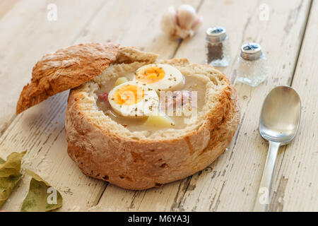 Traditionelle polnische Suppe namens Zurek mit Eiern und Würstchen auf hölzernen Hintergrund Stockfoto