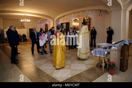 Taufe für Baby in ländlichen Kirche. Priester stand vor der Frau und Mann mit einem Baby auf Händen und Lesen der Bibel. Januar 7,2018. Bucha, Ukraine Stockfoto