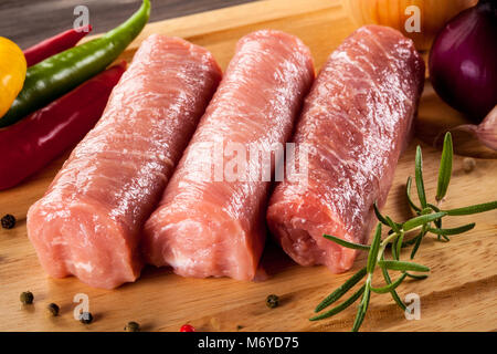 Raw Schweinekoteletts auf Schneidebrett und Gemüse Stockfoto