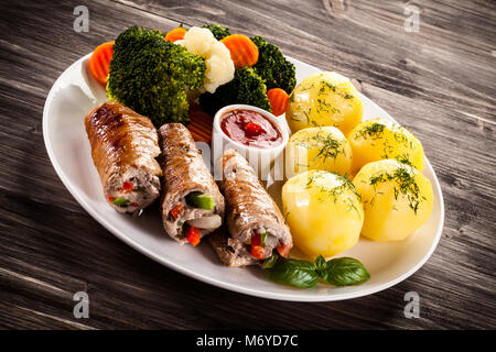 Wickelte Schweinekotelett, gekochte Kartoffeln und Gemüse Stockfoto