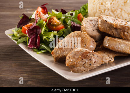 Gebratene Schweinelende, weißer Reis und Salat Stockfoto